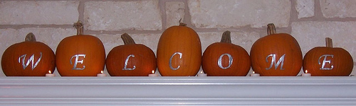 7 pumpkins on mantle with welcome painted in silver (one letter per pumpkin)